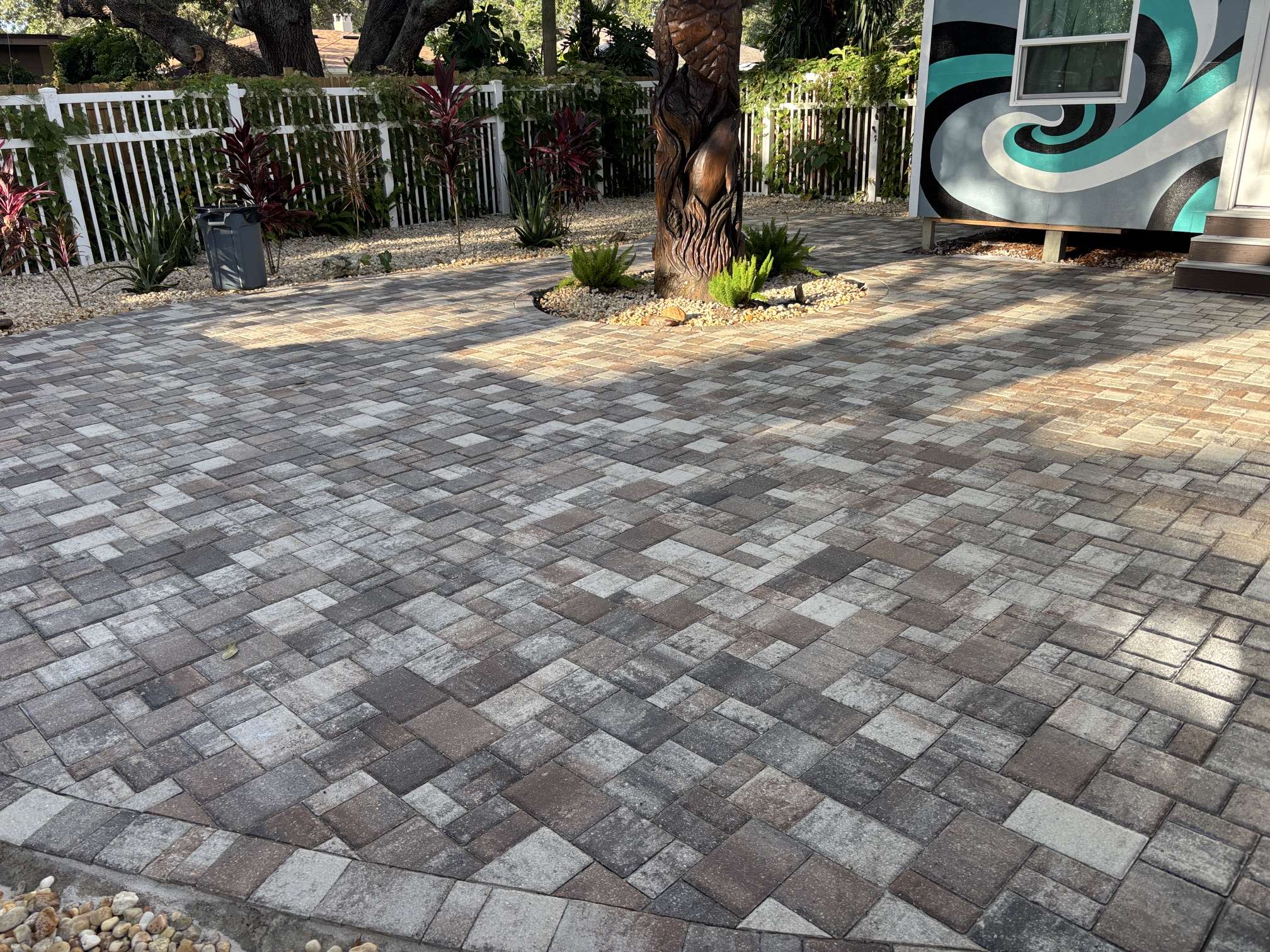 Sealed paver patio in Clearwater, FL featuring a decorative tree carving and mural backdrop