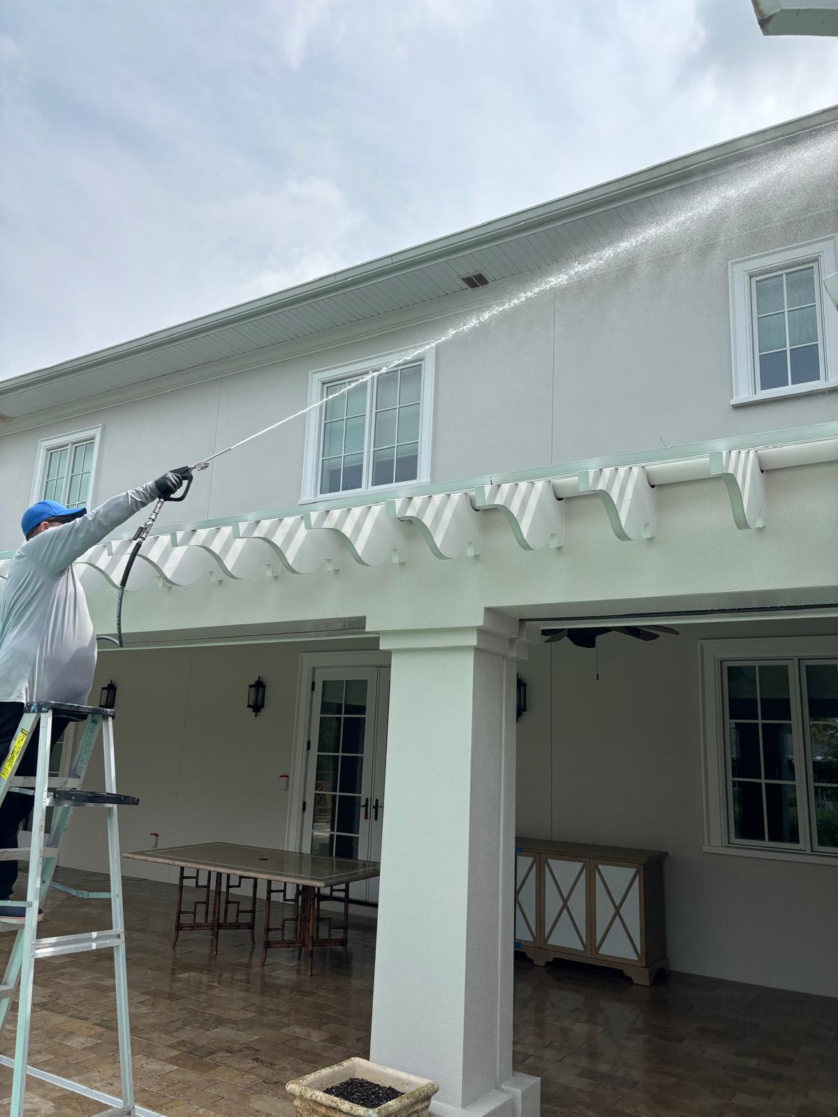 Rusty's Pro Wash & Seal technician soft washing the exterior stucco and eaves of a home
