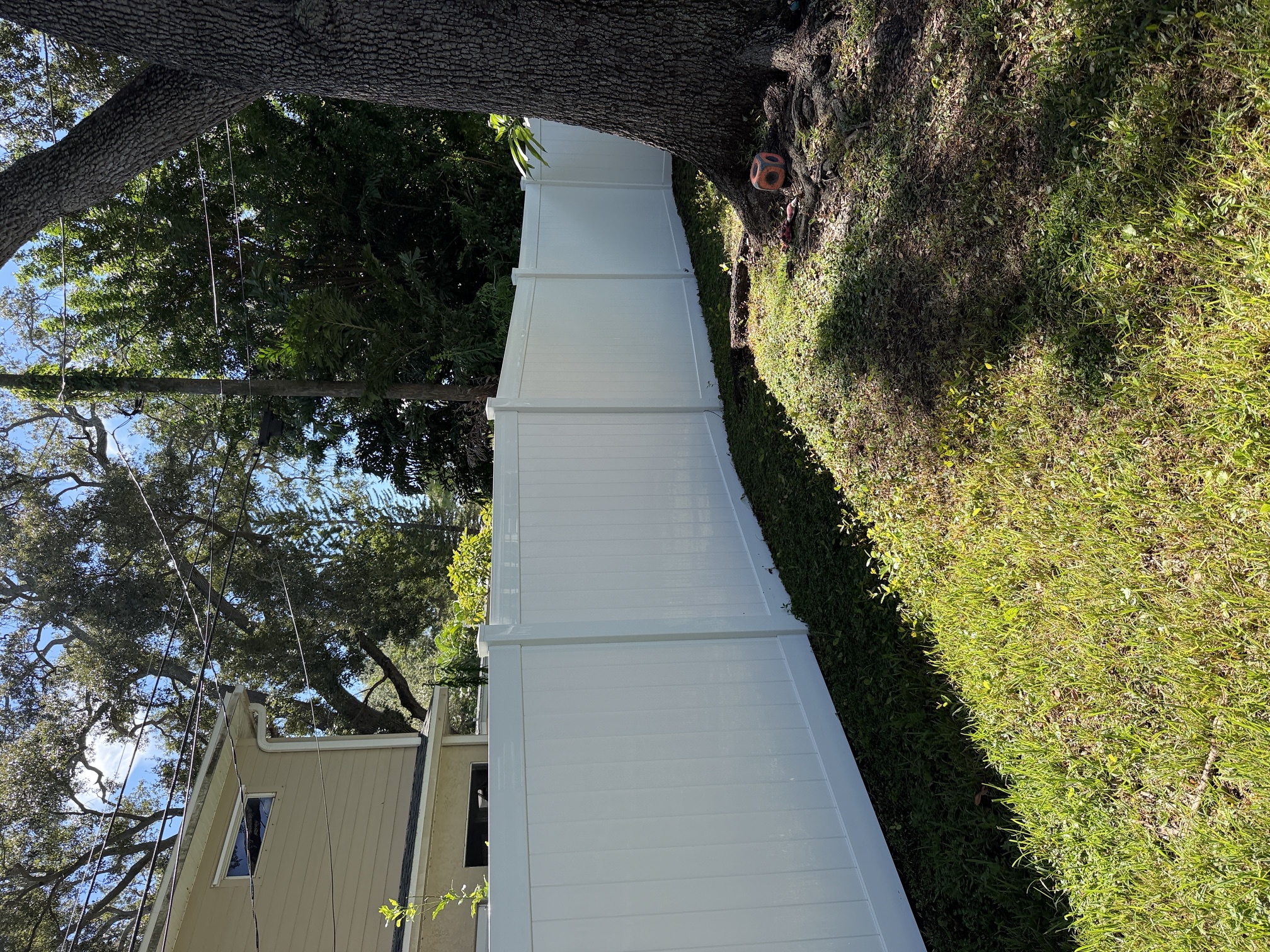 After photo of a clean white vinyl privacy fence under oak tree canopy in Largo, FL